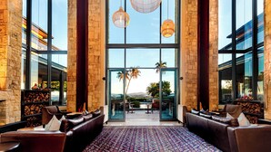 A spacious lobby with leather seating, large windows, and hanging pendant lights.