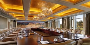 A conference room with a long table, leather chairs, and a chandelier.