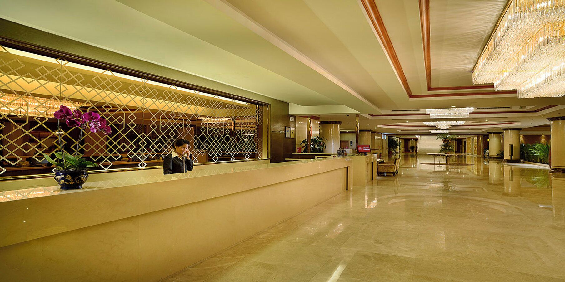 Et hotellets receptionområde med reception, loungeområde og en lysekrone.