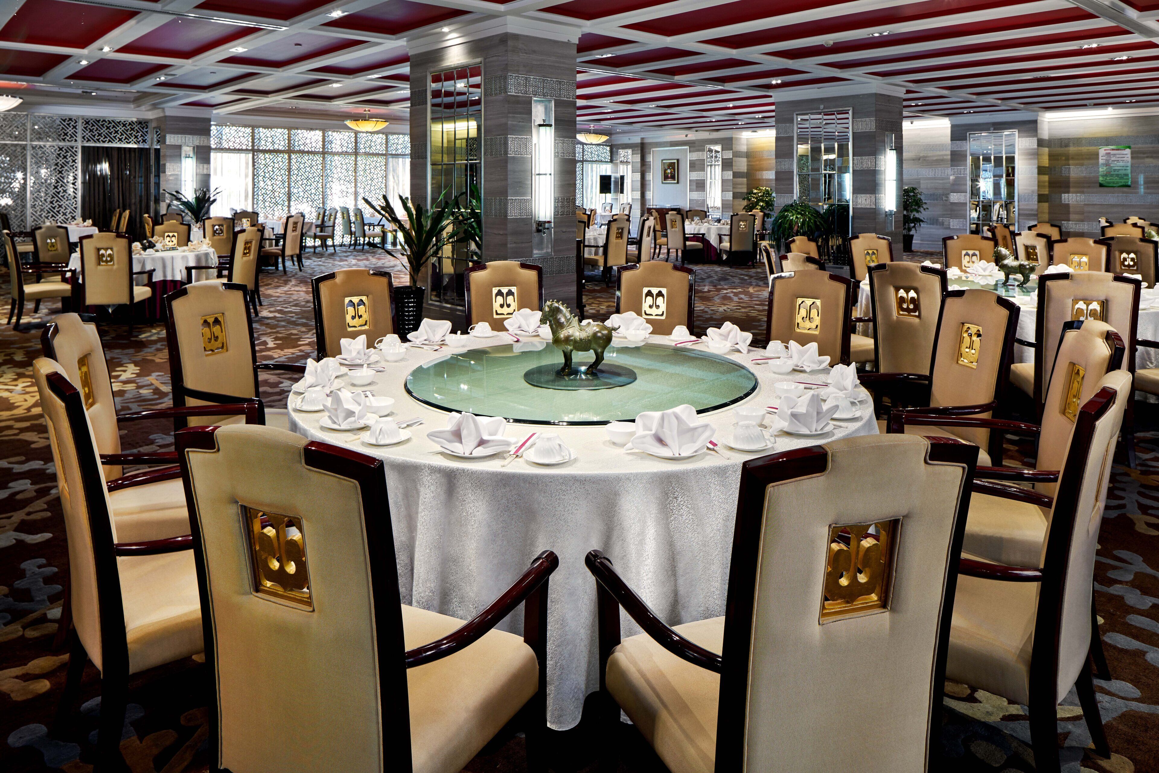 A banquet hall with round tables, chairs, and a central decorative piece.