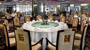 A banquet hall with round tables, chairs, and a central decorative piece.