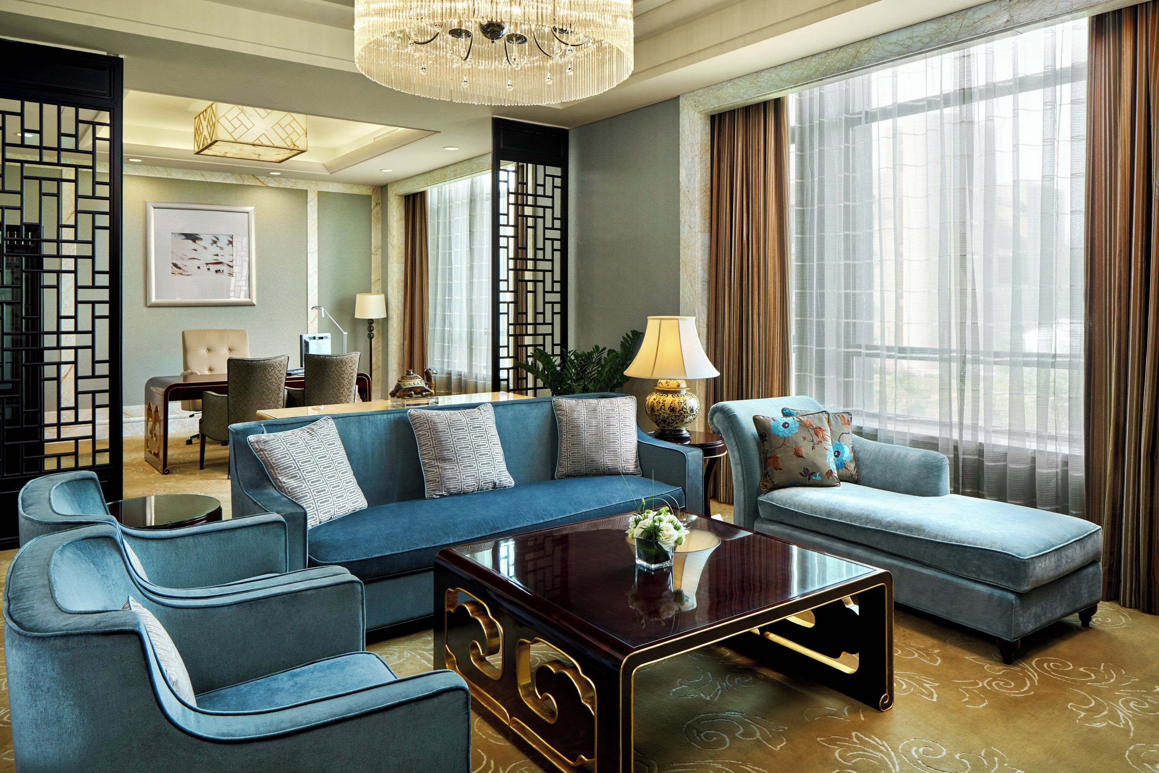 A modern living room with a blue sofa set, a coffee table, and a chandelier.