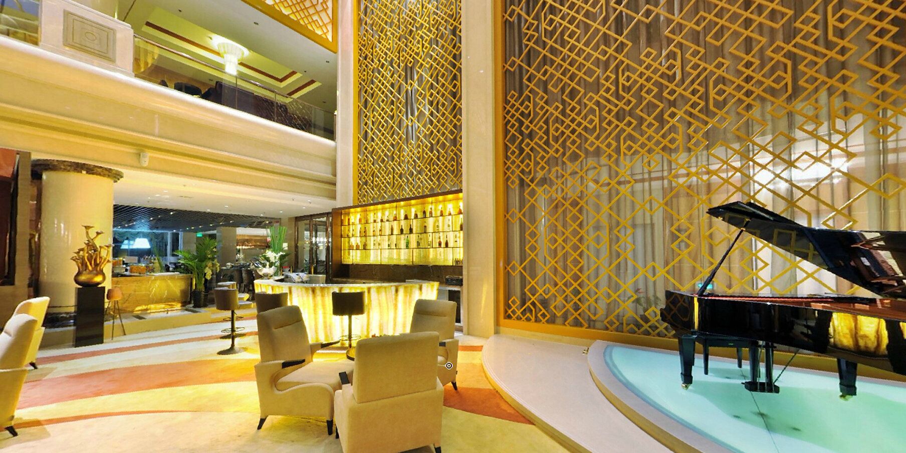 A lobby with a grand piano, seating area, and a bar.