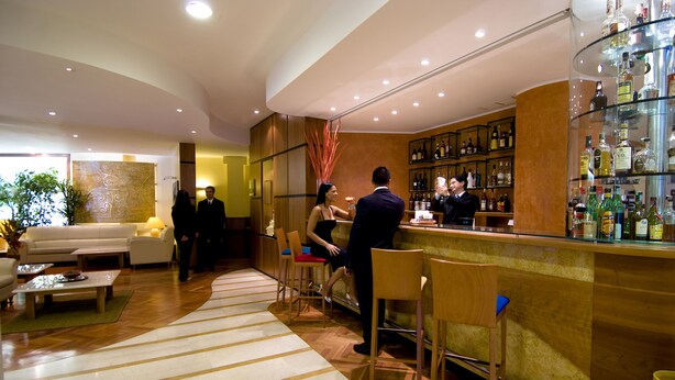 A bar area with a counter, seating, and a display of liquor bottles. - Holiday Inn Cagliari by IHG (Cagliari)