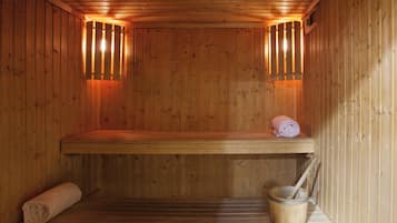 A wooden sauna with benches, a towel, and a bucket.