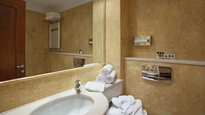 A bathroom with a sink, mirror, towel rack, and toiletries shelf. - Holiday Inn Cagliari by IHG (Cagliari)