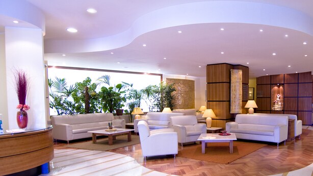 A spacious lobby with multiple seating areas, a reception desk, and a bar. - Holiday Inn Cagliari by IHG (Cagliari)