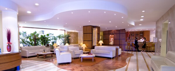 Un hall d’entrée spacieux avec plusieurs coins salon, un comptoir d’accueil et un bar.
