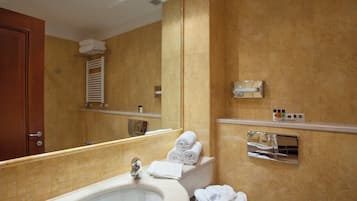 A bathroom with a large bathtub, a sink, a mirror, and a towel rack.