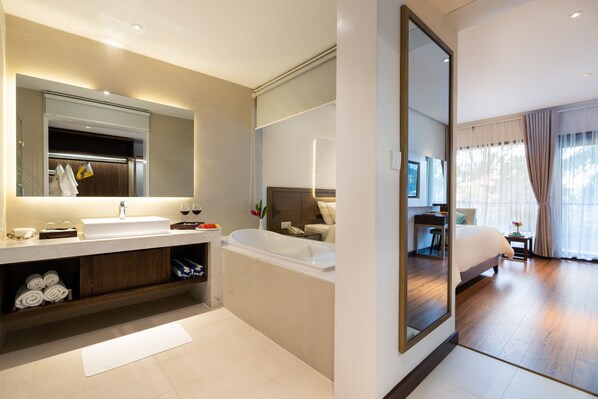 A modern hotel bathroom with a large mirror, a bathtub, and a sink.
