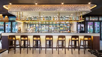 A bar area with multiple seating options and a variety of bottles displayed on shelves.