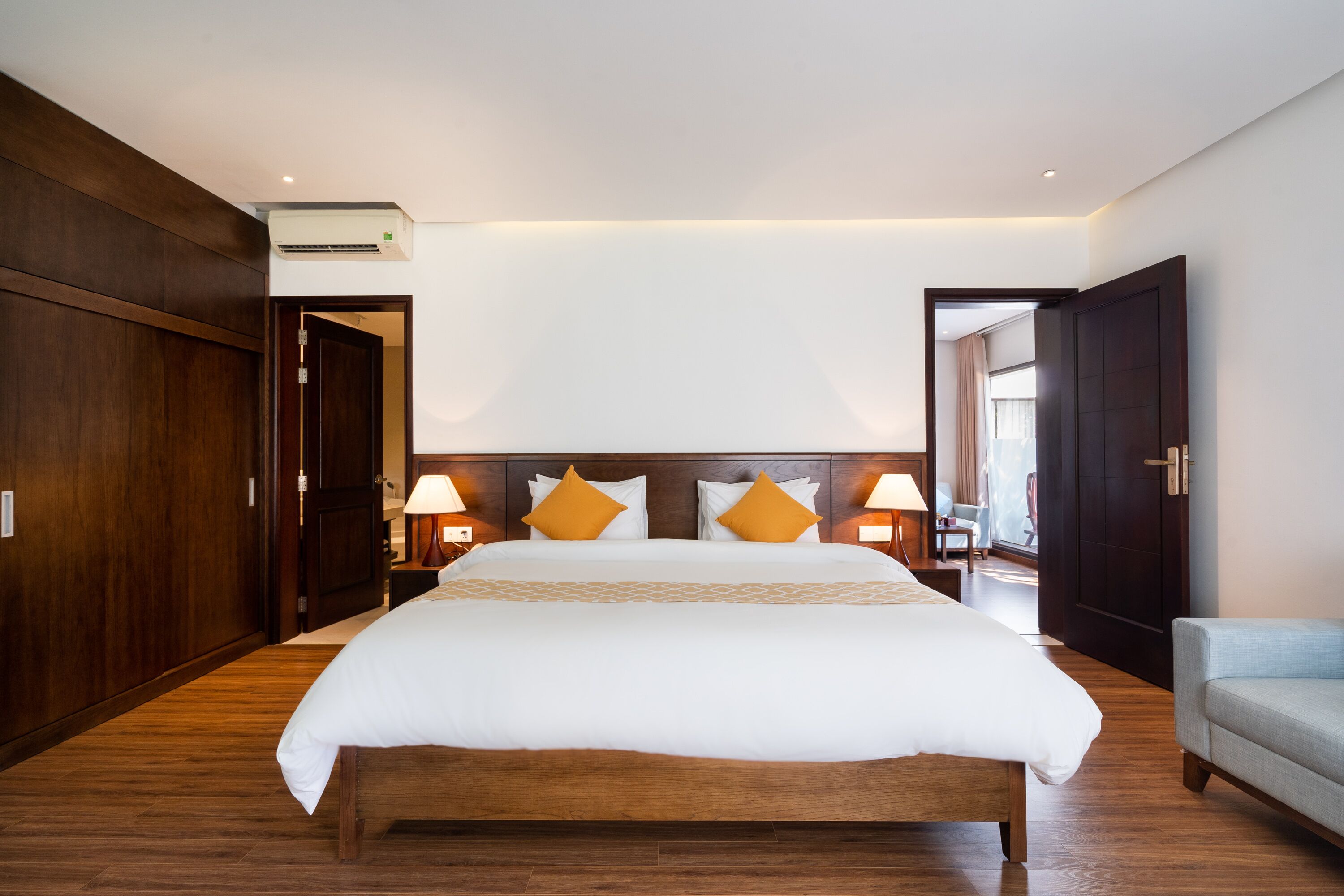 Habitación de hotel con una cama grande, suelo de madera, armario y zona de estar.