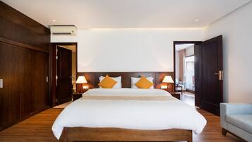 Habitación de hotel con una cama grande, suelo de madera, armario y zona de estar.
