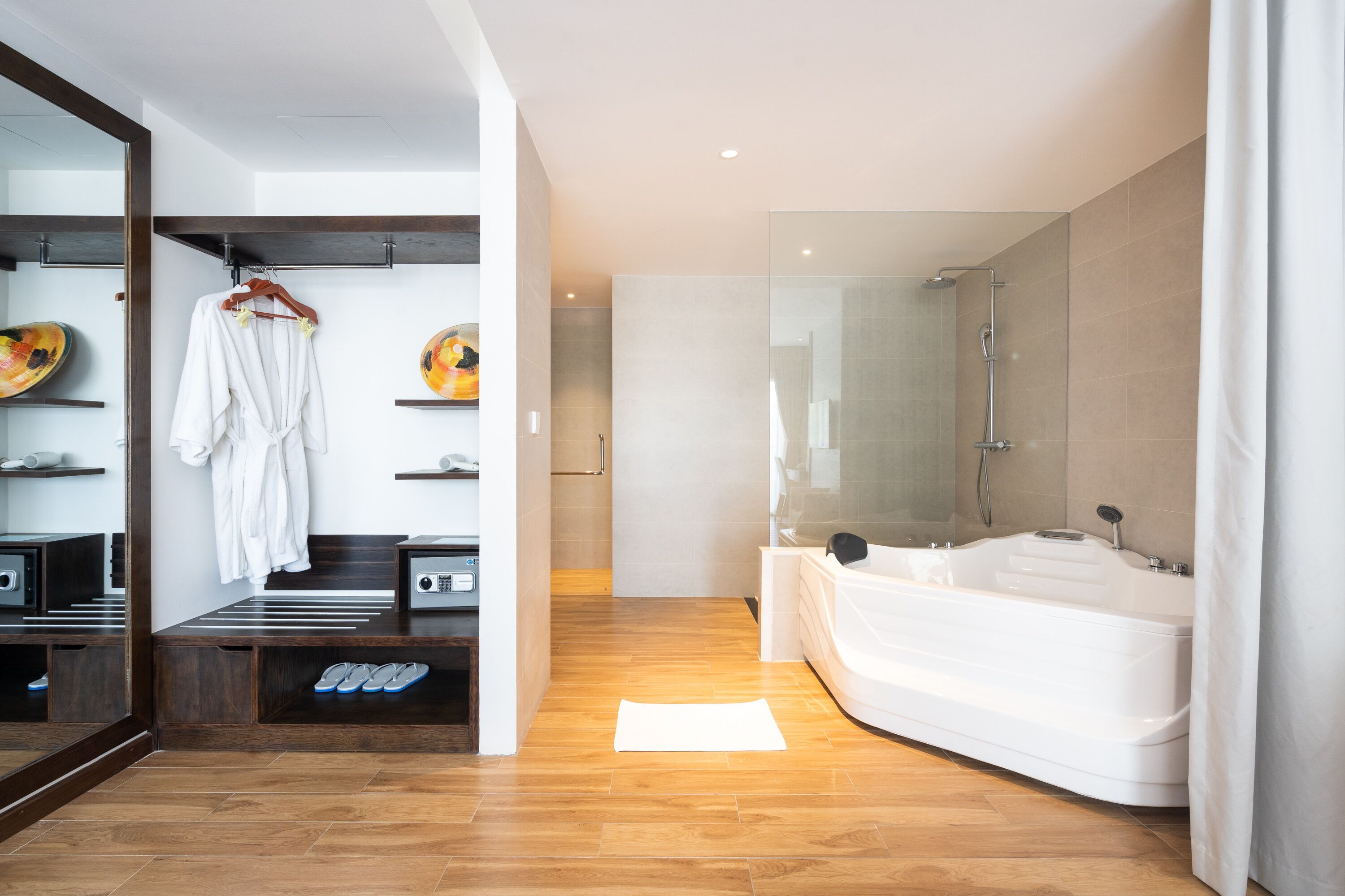 Une salle de bain moderne avec un grand miroir, une douche à l’italienne, une baignoire et un peignoir suspendu à un porte-serviettes.