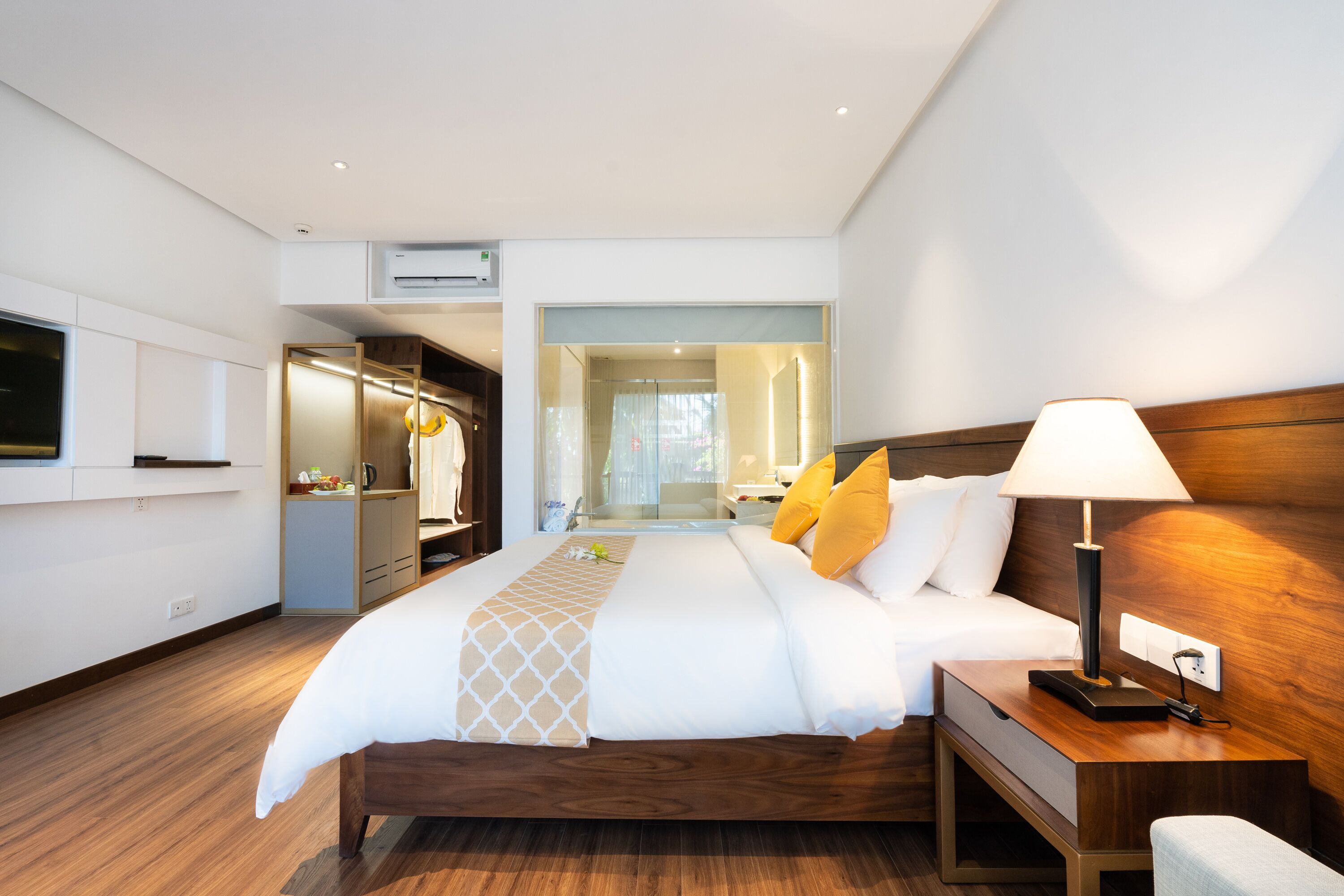 A modern hotel room with a large bed, bedside table, and a TV mounted on the wall.