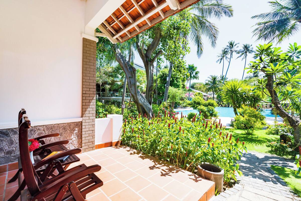 A patio with a wooden chair and a potted plant.