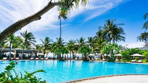 Una piscina grande rodeada de palmeras y sillas de descanso.