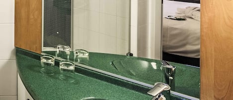A bathroom with a green sink, a mirror, and a shower.