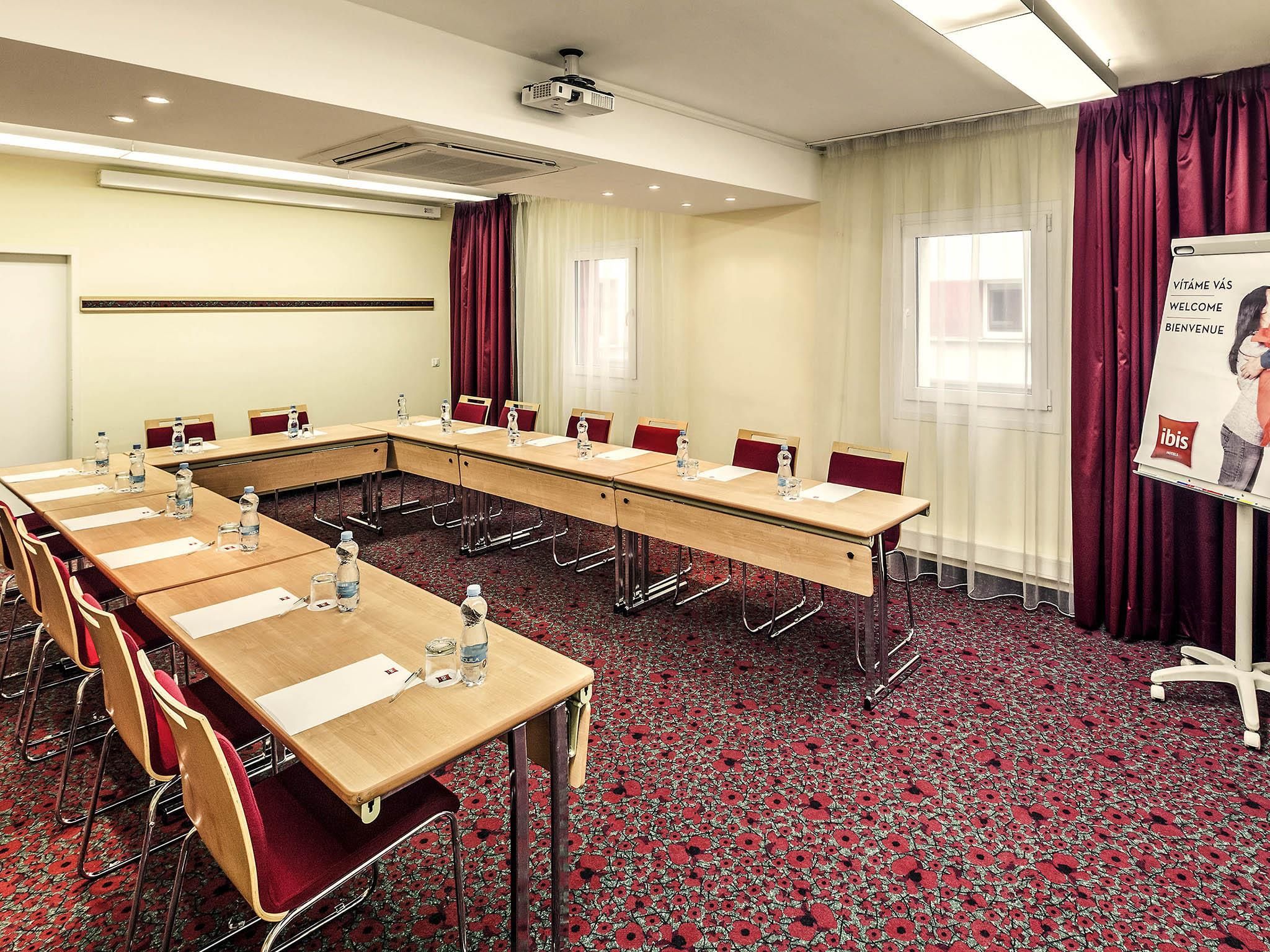 A conference room with a long table, chairs, water bottles, and a projector screen.