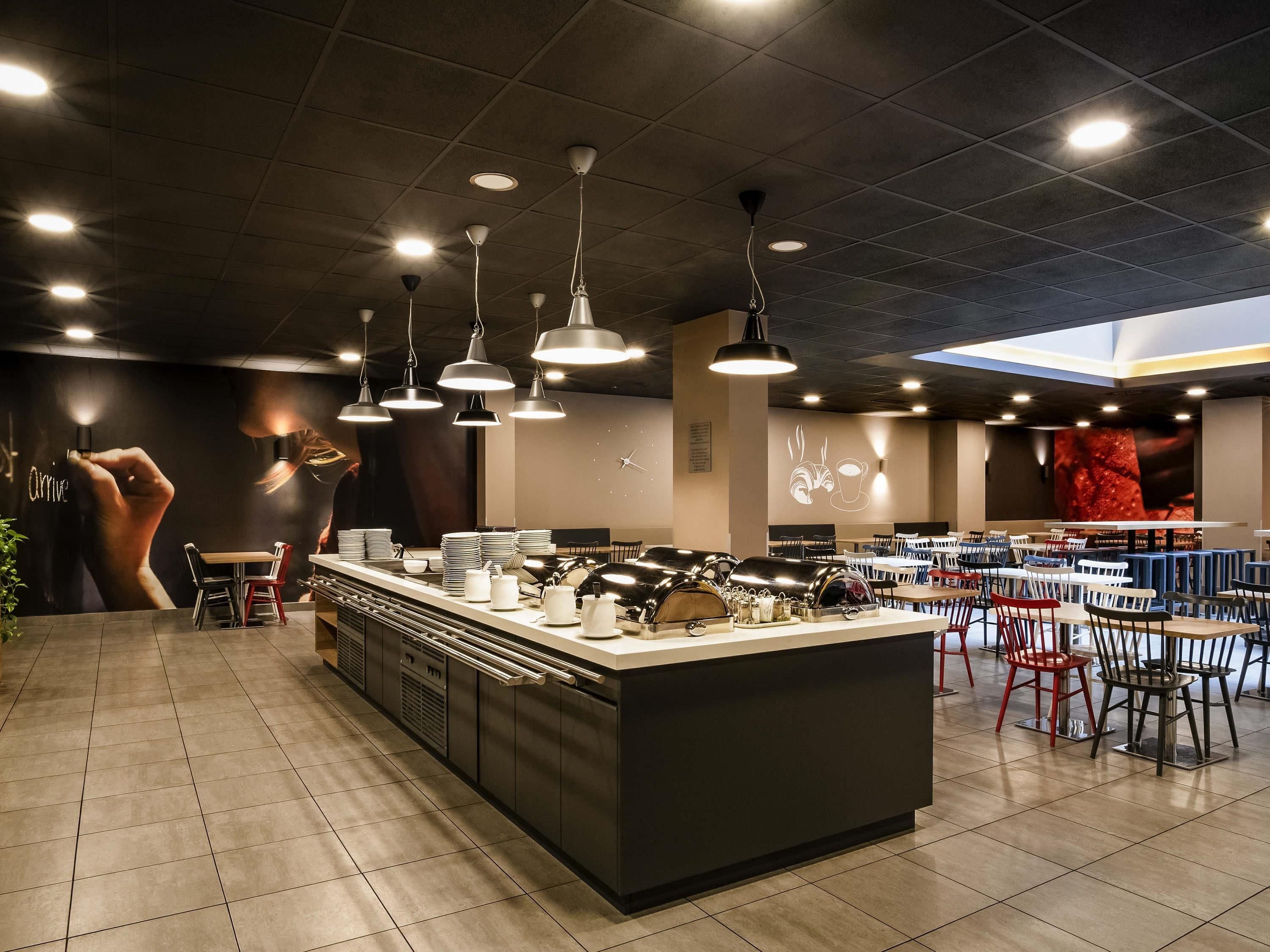 Un restaurante moderno con una isla central, múltiples luces colgantes y piso de baldosas.