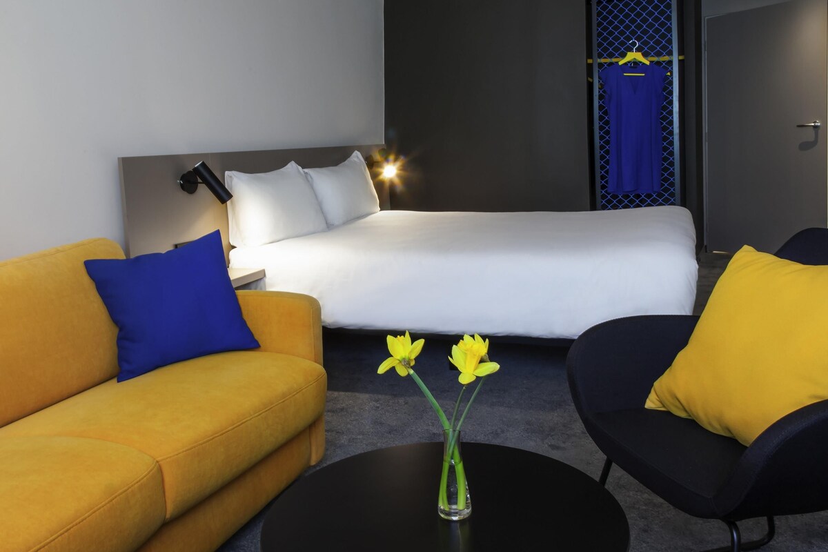 Una habitación de hotel moderna con una cama, un sofá, una silla y una mesa de centro.