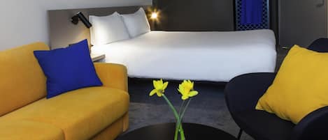 Una habitación de hotel moderna con una cama, un sofá, una silla y una mesa de centro.