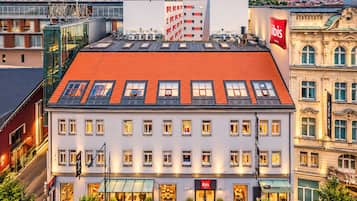 A hotel with a red-tiled roof, multiple windows, and a glass facade.
