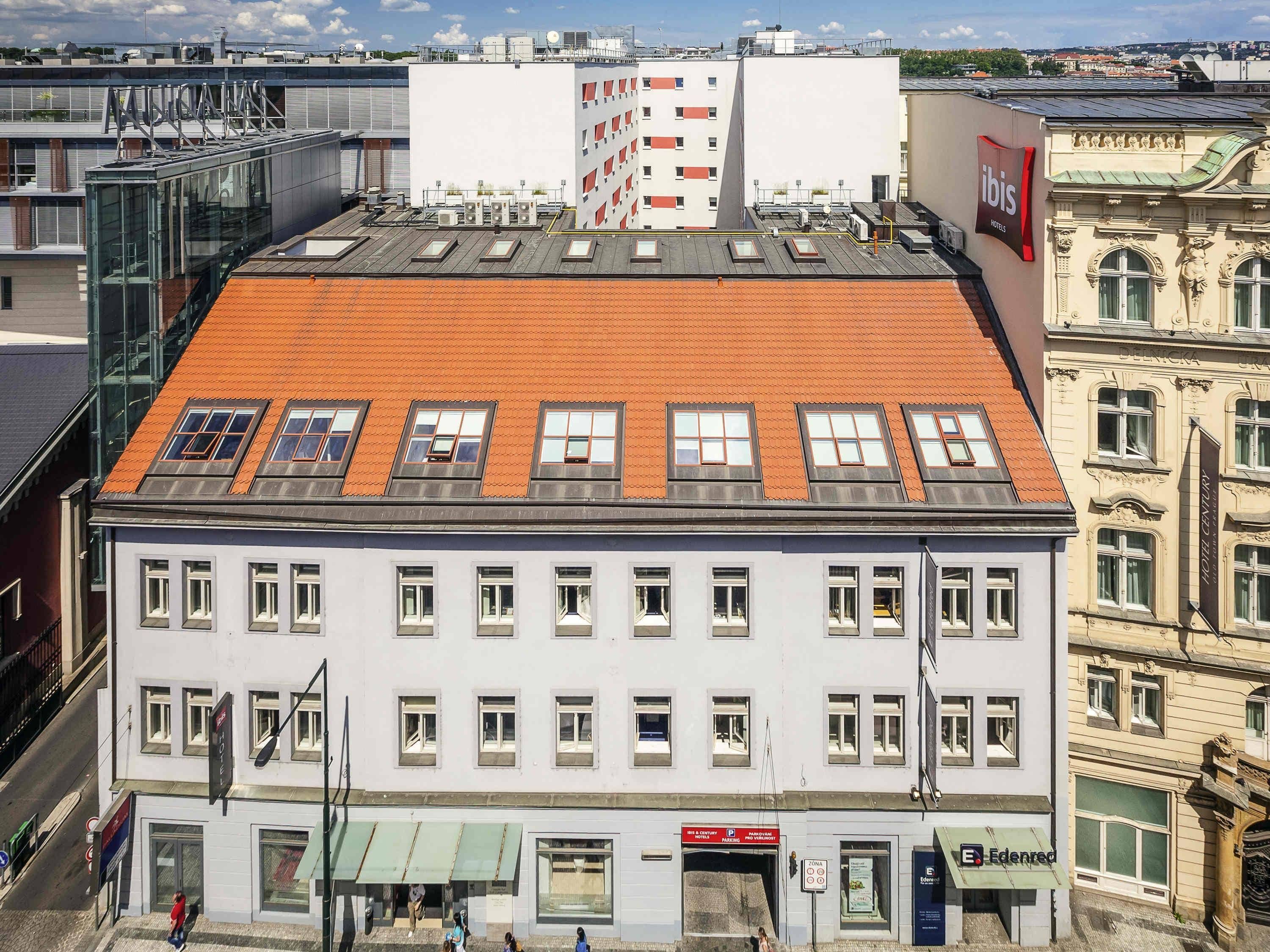 A hotel with a red-tiled roof, multiple windows, and a modern glass facade.