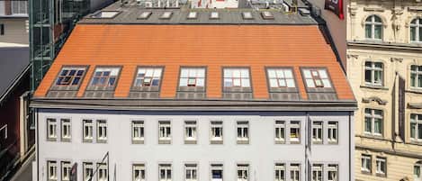 A hotel with a red-tiled roof, multiple windows, and a modern glass facade.