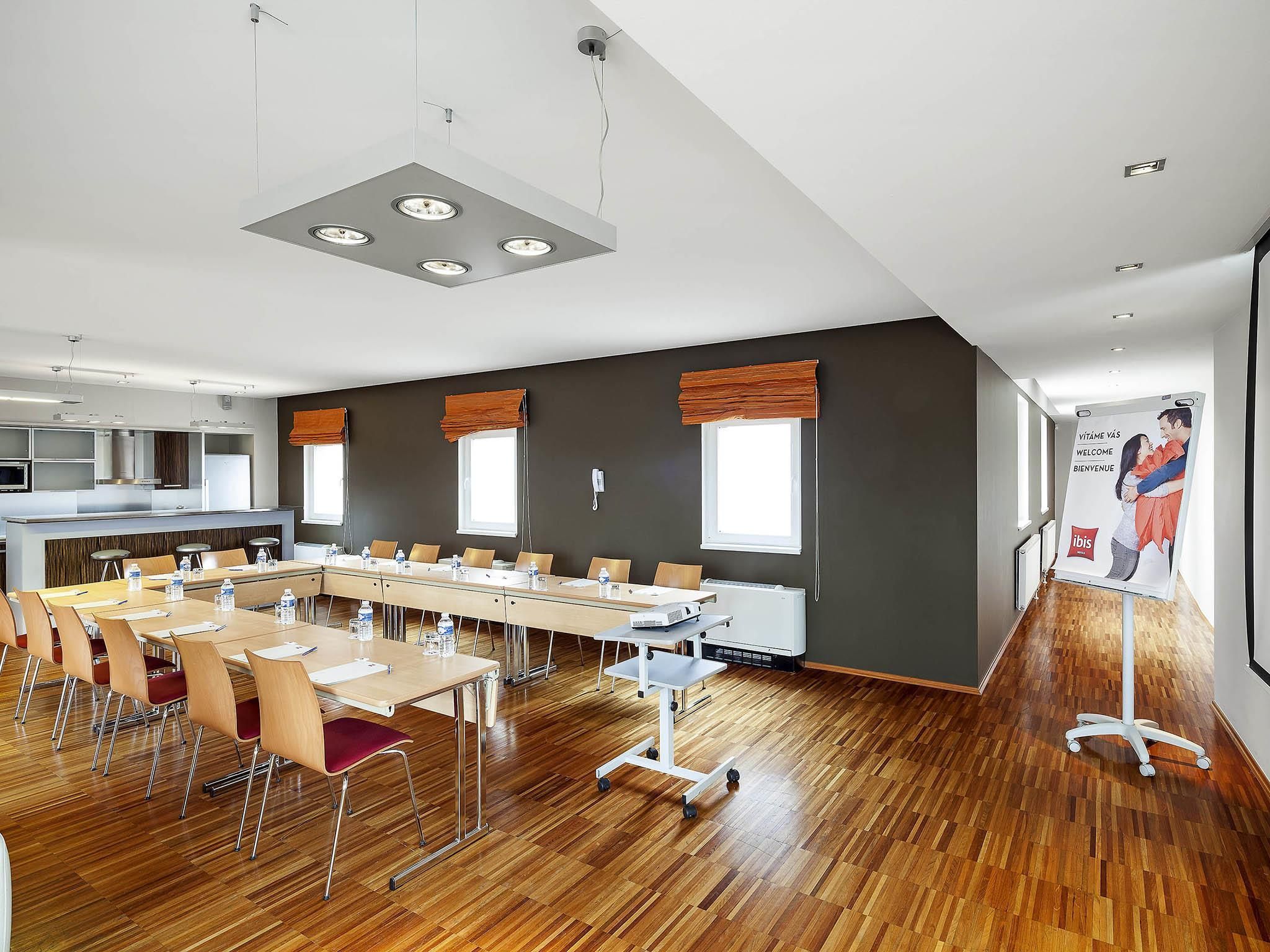 Een moderne vergaderruimte met een lange tafel, stoelen en een beamerstandaard.