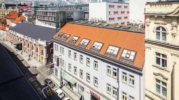 Um edifício de vários andares com telhado de telhas vermelhas, janelas amplas e uma combinação de estilos arquitetônicos, incluindo elementos tradicionais e modernos.