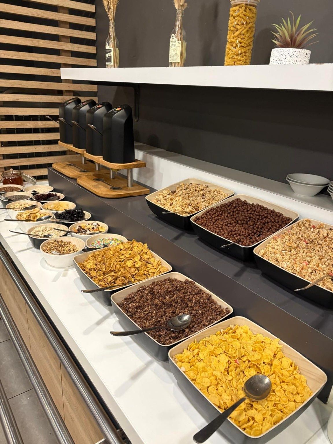 Un bufé con diversas opciones de comida, incluyendo cereales, frutos secos y frutas deshidratadas.
