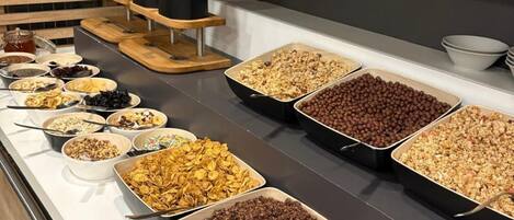 Un bufé con diversas opciones de comida, incluyendo cereales, frutos secos y frutas deshidratadas.