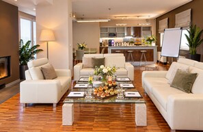 A modern living room with a glass coffee table, white sofas, and a kitchen in the background. - ibis Praha Old Town (Prague)