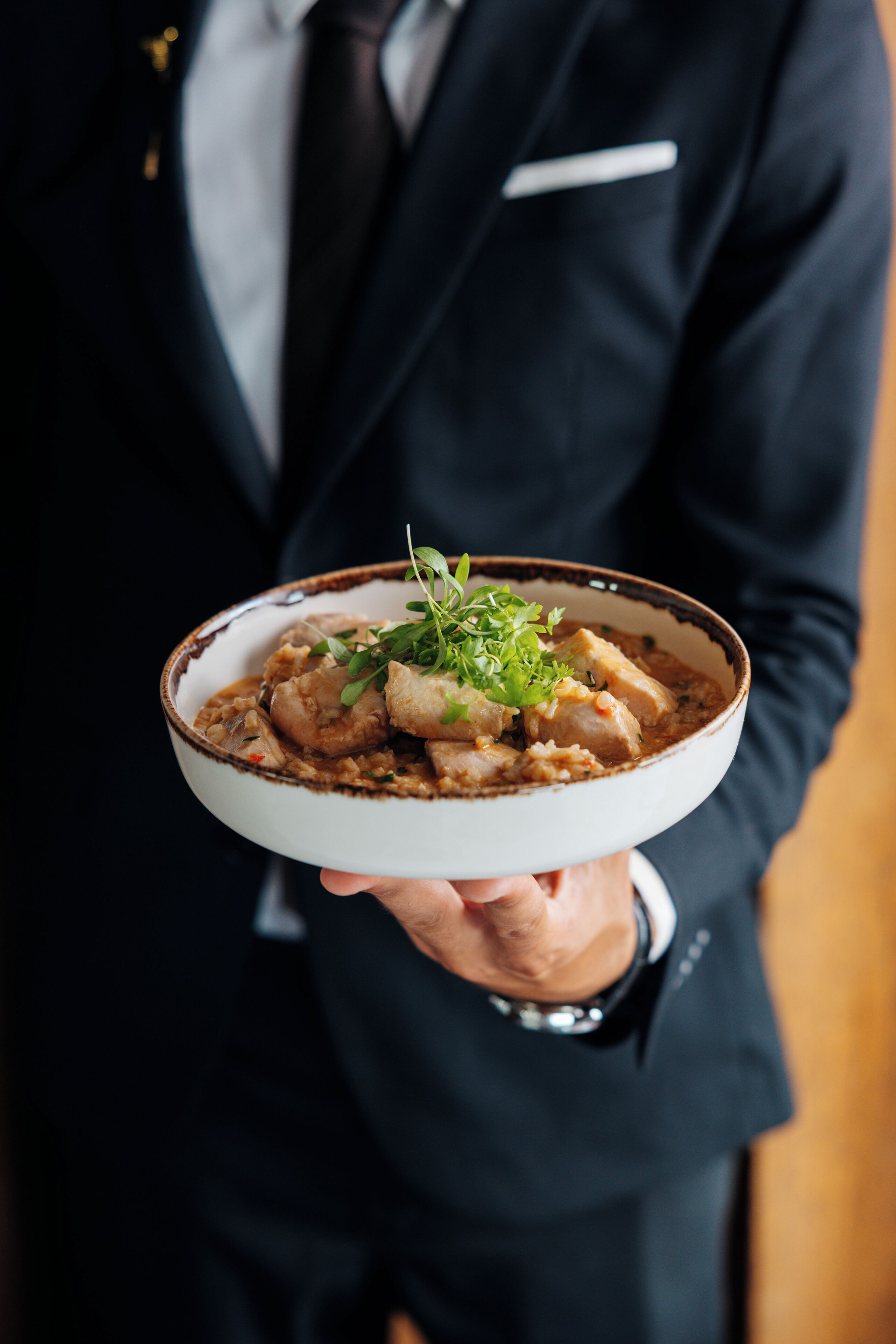 A person holding a bowl of food with a garnish.