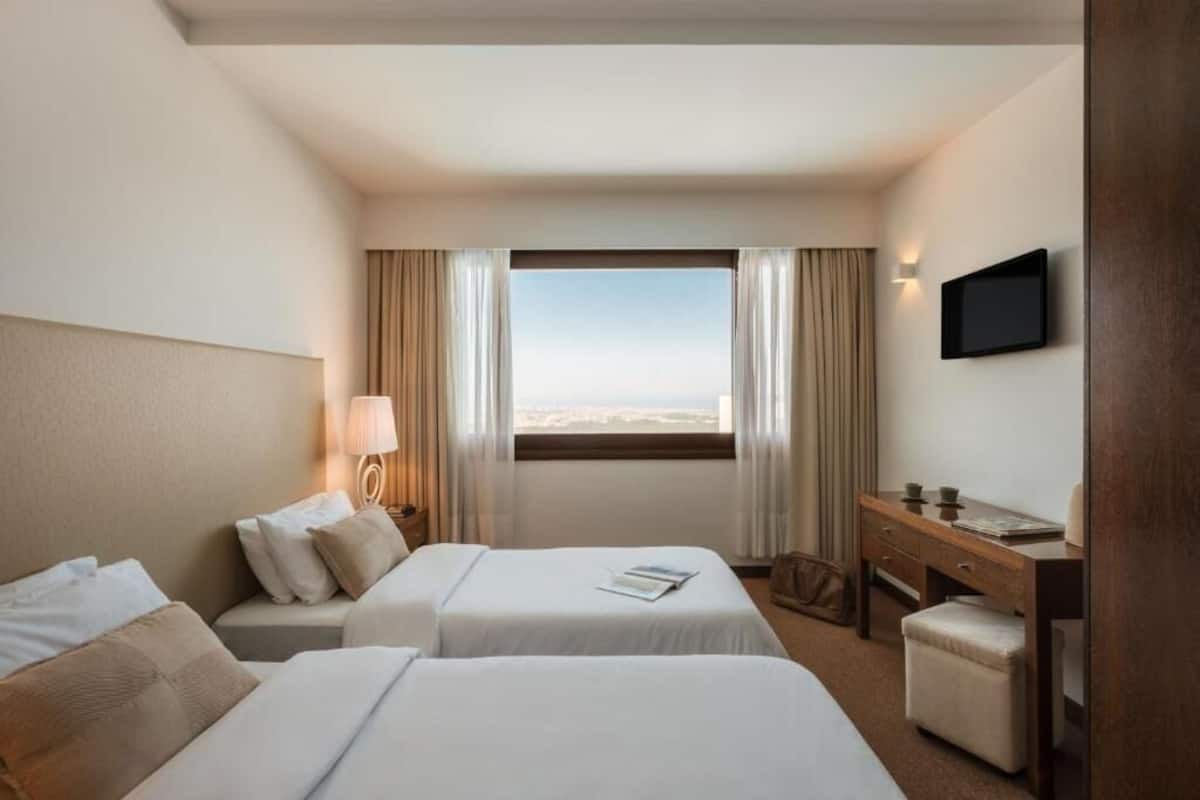 A hotel room with two beds, a desk, a chair, a TV, and a window with curtains.