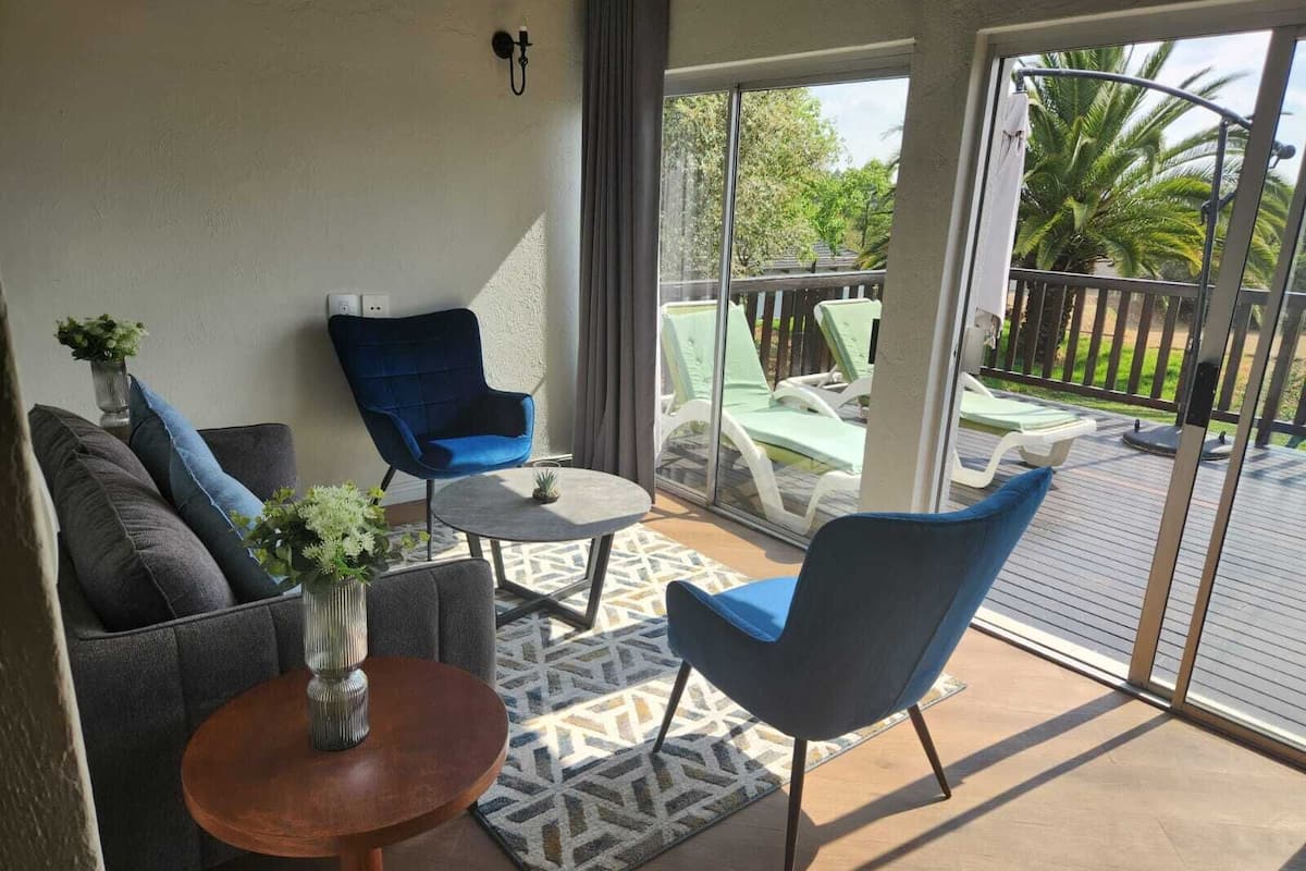 Een balkon met een bank, stoelen en een kleine tafel.