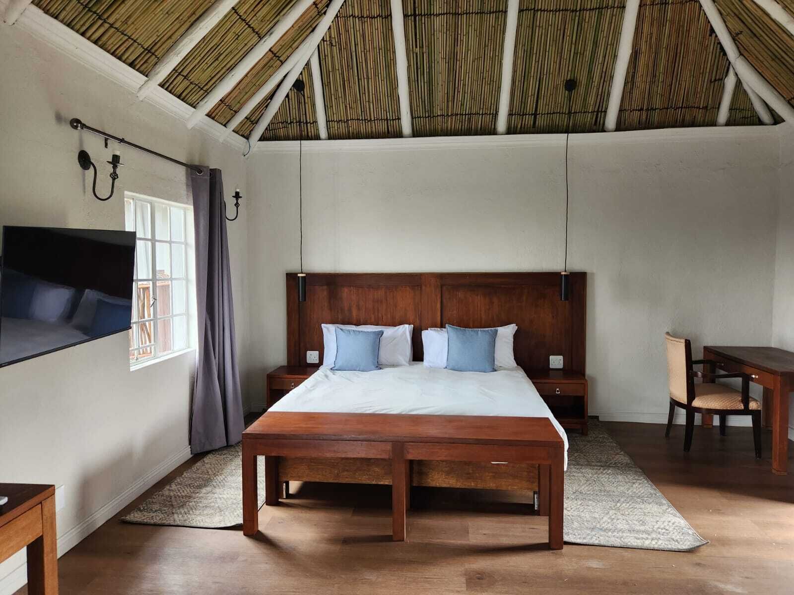 A bedroom with a large bed, bedside tables, a desk, and a chair.