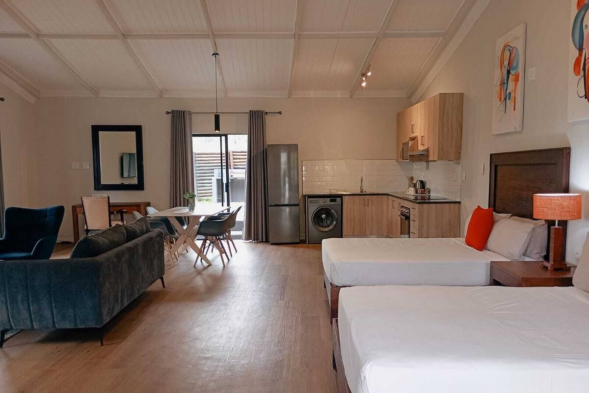 Een moderne hotelkamer met een bank, twee bedden, een eethoek en een keuken.