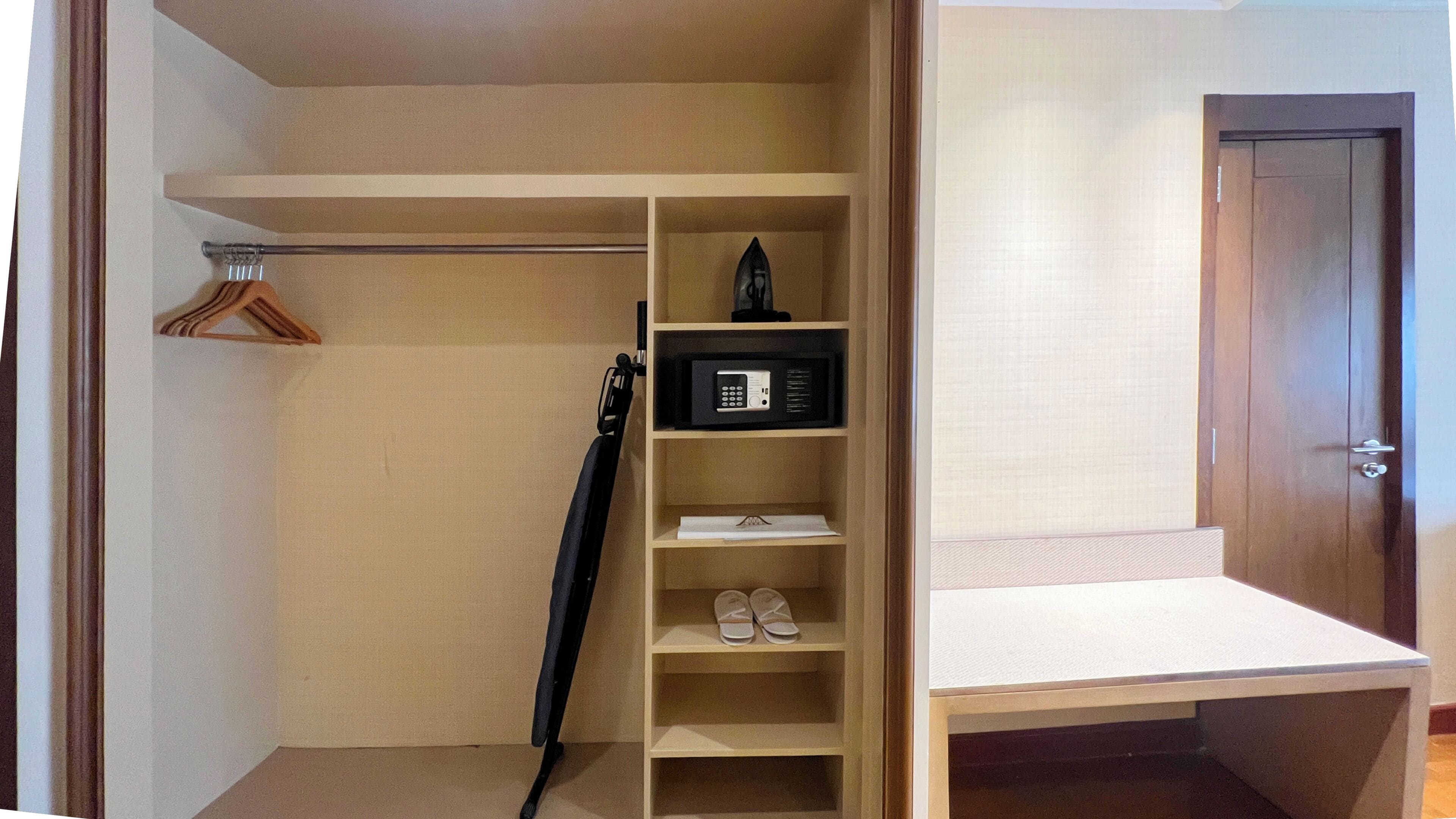 Un armario vestidor con una barra para colgar, un estante para zapatos y un microondas.