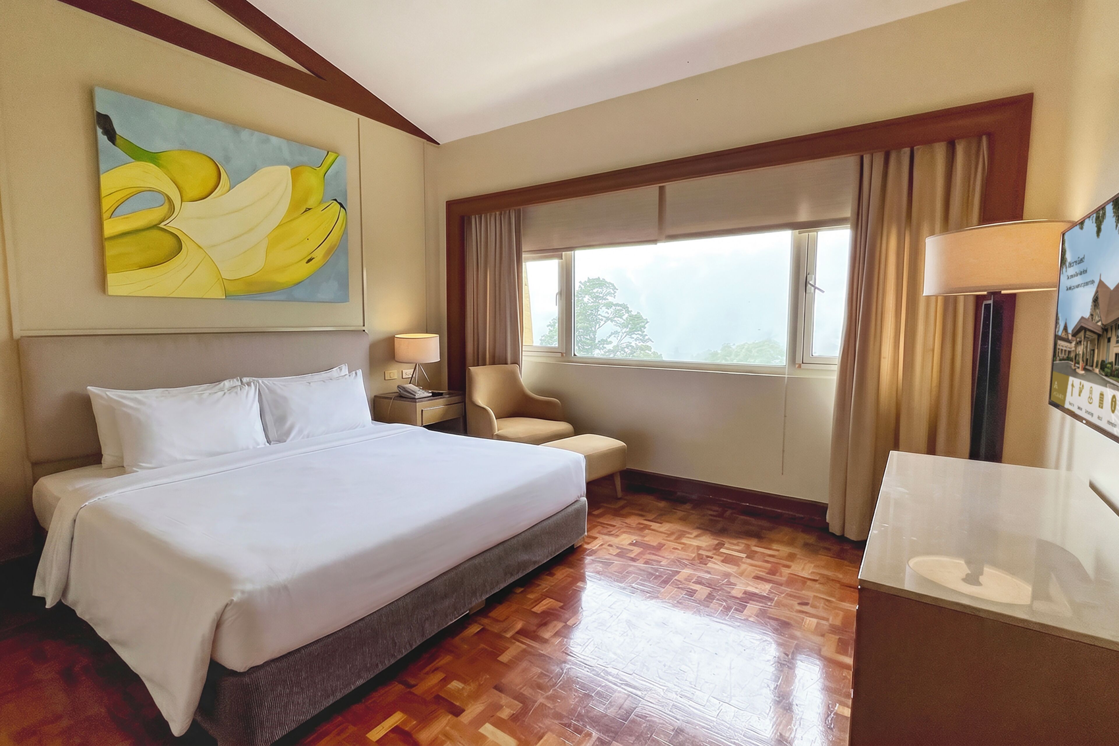 Habitación de hotel con cama, escritorio, silla, ventana con cortinas y un cuadro en la pared.