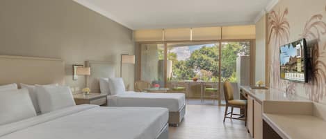 Habitación de hotel con dos camas, un escritorio, una silla, un televisor y un balcón con vistas.