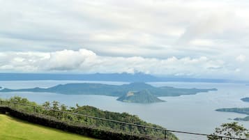 Vista panorámica de un paisaje costero con un primer plano de césped, una barandilla metálica e islas distantes.