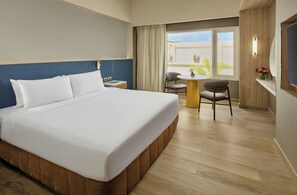 A hotel room with a large bed, a small table, two chairs, a window with curtains, and a view of the outside. - Taal Vista Hotel (Tagaytay)