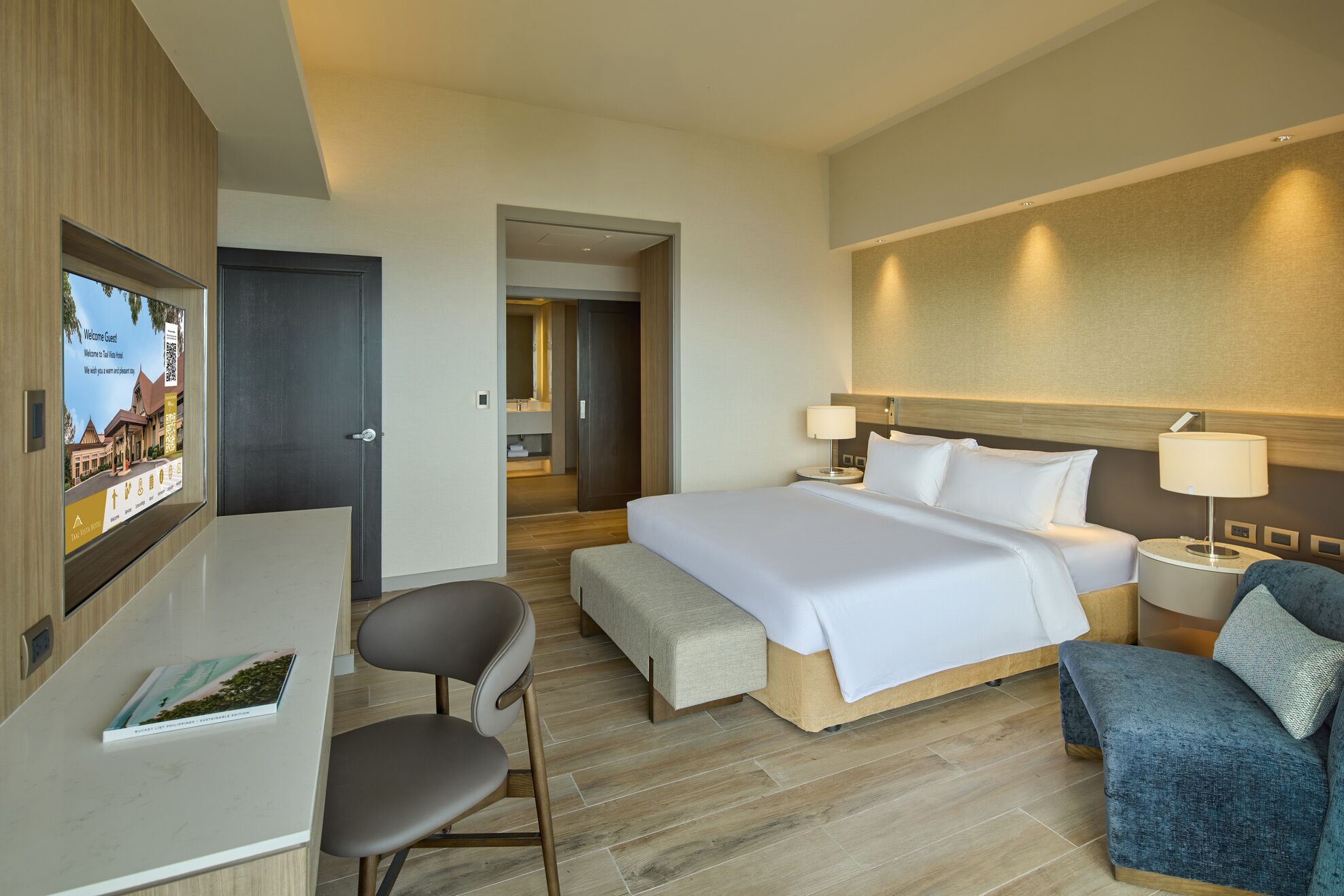 Una habitación de hotel con cama, mesitas de noche, escritorio y una silla.