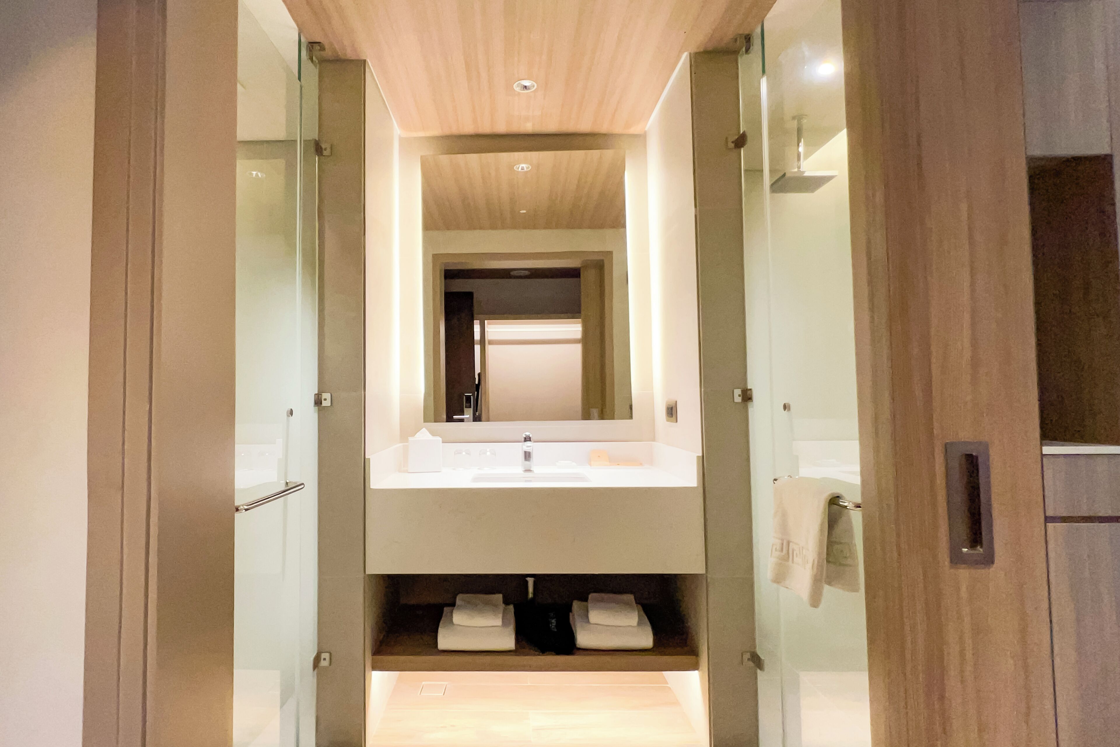 A modern bathroom with a large mirror, a sink, and a towel rack.