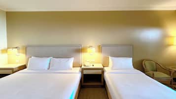 Habitación de hotel con dos camas, mesitas de noche, lámparas y una silla.