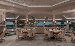 A spacious dining area with high ceilings and large windows overlooking a scenic view. - Taal Vista Hotel (Tagaytay)