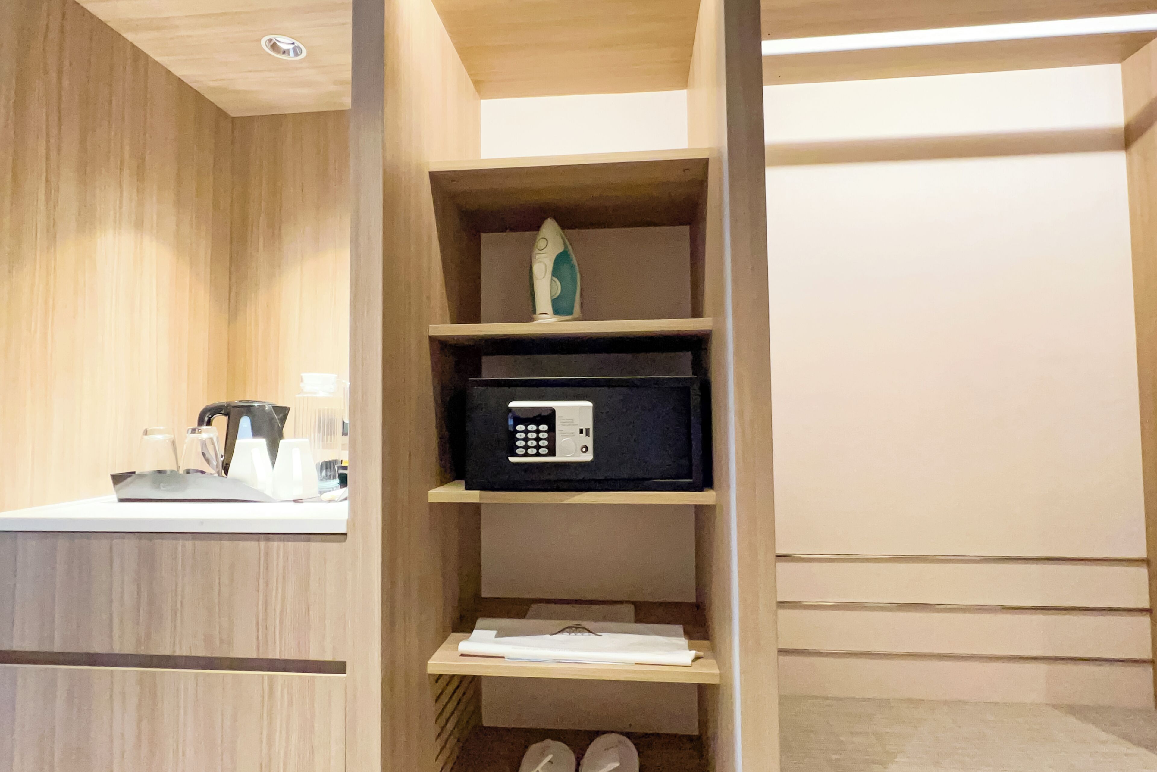 A hotel room with a wooden vanity, a microwave, and a shelf with a decorative item.