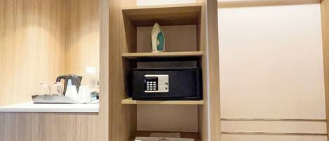 A hotel room with a wooden vanity, a microwave, and a shelf with a decorative item.